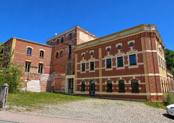 Historische Backsteinbrauerei in Greiz mit gelben Fensterrahmen und gepflastertem Hof